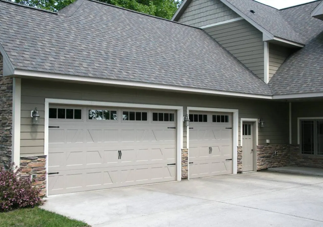 White paneled garage doors installed on a gray home