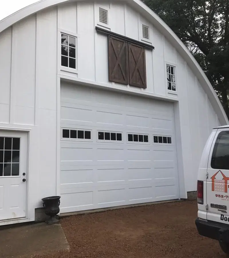 White overhead door with top windows on a gambrel-roof building
